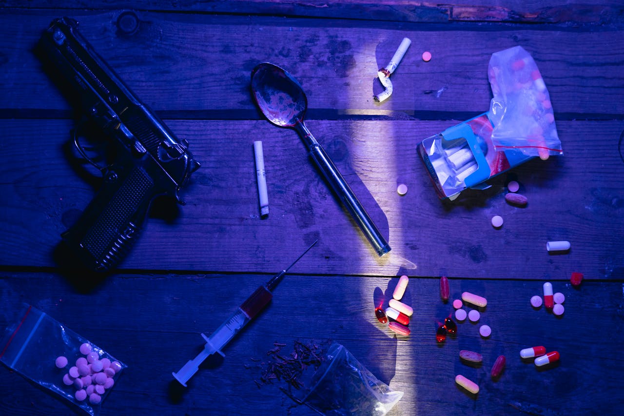 About Intriguing still life image depicting pills, a gun, and syringe under dramatic lighting.