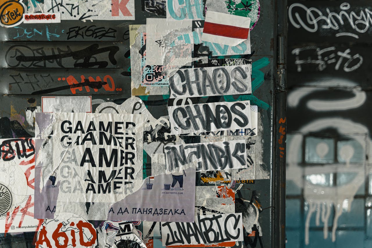 Vibrant urban scene of graffiti and layered posters on a city wall, capturing street art culture.